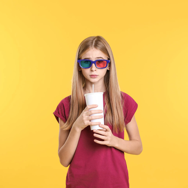 Emotional teenage girl with 3D glasses and beverage during cinema show on color background - Fotoğraf, Görsel