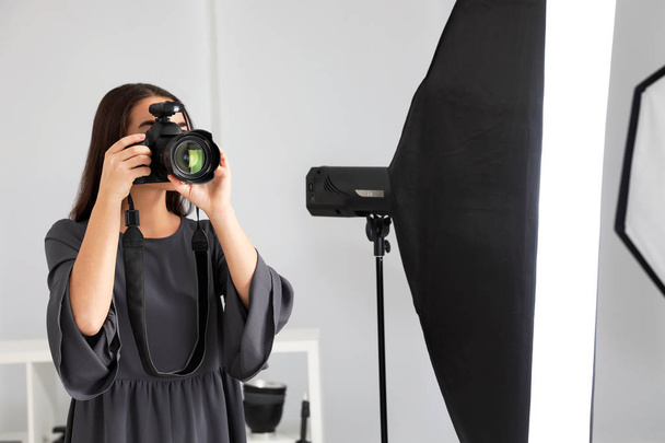 Young woman with professional camera in photo studio - Фото, зображення