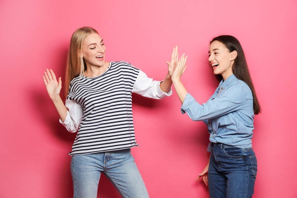 Young women celebrating victory against color background - Foto, Imagen