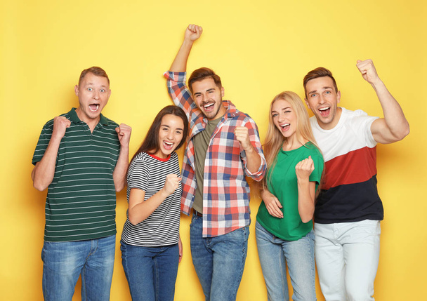 Group of friends celebrating victory against color background - Фото, изображение
