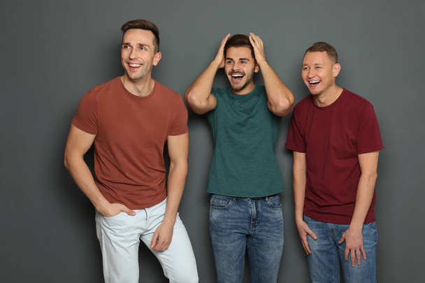 Group of friends laughing together against gray background - Foto, Imagem