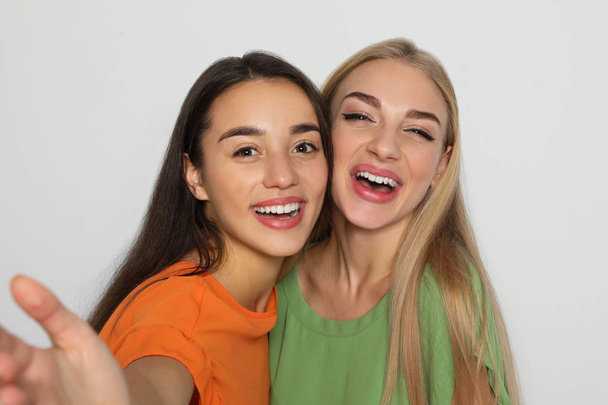 Young women laughing together against light background - Fotoğraf, Görsel