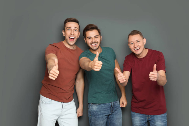Group of friends celebrating victory against gray background - Foto, Bild