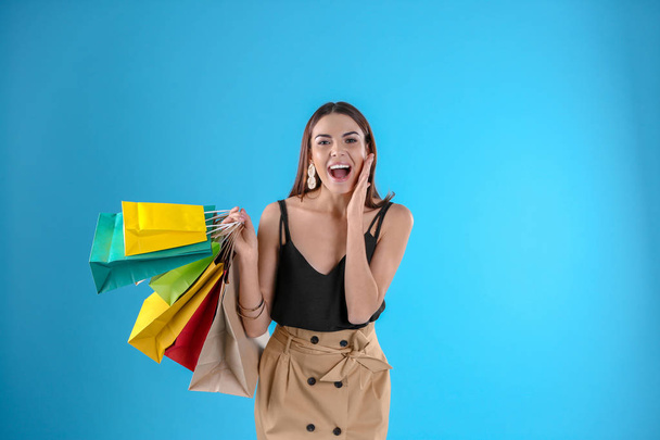 Young woman with shopping bags on color background. Space for text - Fotó, kép