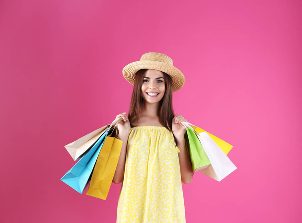 Young woman with shopping bags on color background - Fotografie, Obrázek