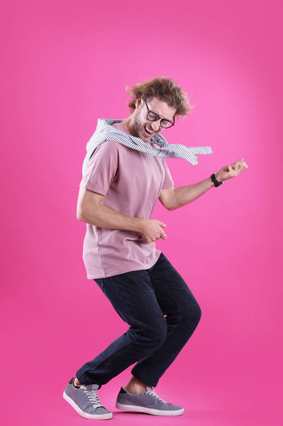 Young man playing air guitar on color background - 写真・画像