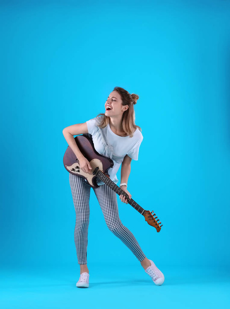 Young woman playing electric guitar on color background - Zdjęcie, obraz