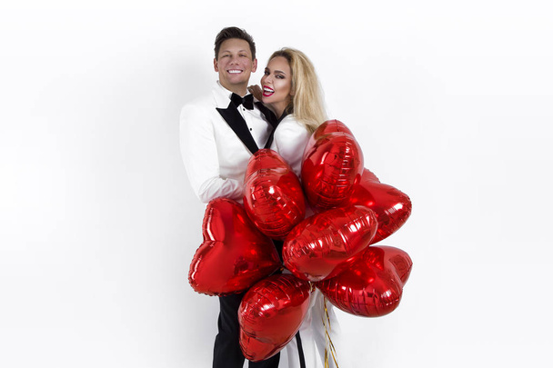 Feliz casal bonito posando no fundo branco e segurando balões coração. Dia dos Namorados. - Imagem
 - Foto, Imagem