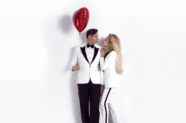 Счастливая прекрасная пара позирует на белом фоне и держит сердечко из шариков. День Святого Валентина. - Образ
 - Фото, изображение