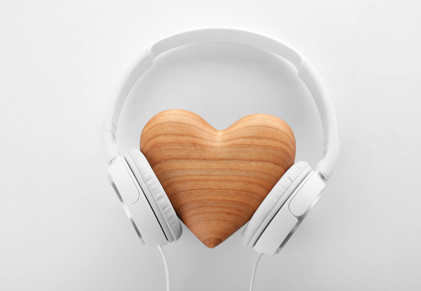 Headphones and wooden heart on white background, top view - Fotó, kép