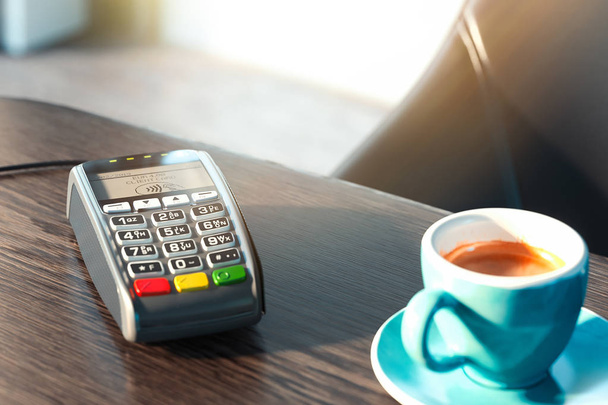 Terminal płatniczy POS i telefon komórkowy w nowoczesną kawiarnię. Koncepcja płatności NFC. renderowania 3D. Filiżanka kawy jest na pierwszym planie. - Zdjęcie, obraz