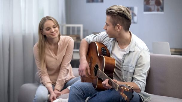 Boy in love playing guitar to girlfriend conquering her heart, romantic date - Photo, image