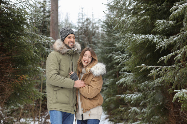 Couple in conifer forest on snowy day, space for text. Winter vacation - Foto, Bild