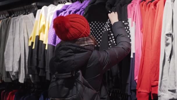 Nainen valitsemalla muoti vaatteita vähittäiskaupassa kaupungin ostoskeskuksessa. Ostokset käsite
. - Materiaali, video