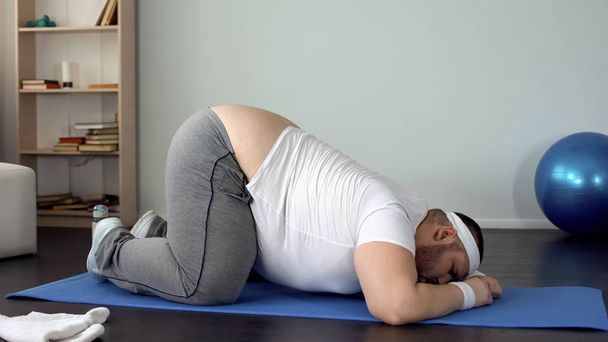 Motivated chubby male stretching with effort at home, will power, weight loss - Photo, Image