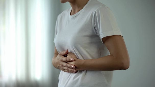 Mulher com dor de estômago tocando barriga, sofrendo de gastrite, pancreatite
 - Foto, Imagem