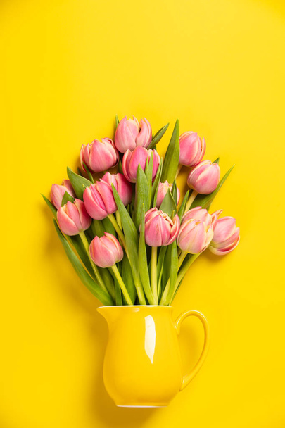 This feminine, floral stock photograph features pretty Fresh pink tulips in a jug on yellow background. Easily downloaded, this stock photo is perfect to use with your website, social media digital marketing. - Fotó, kép