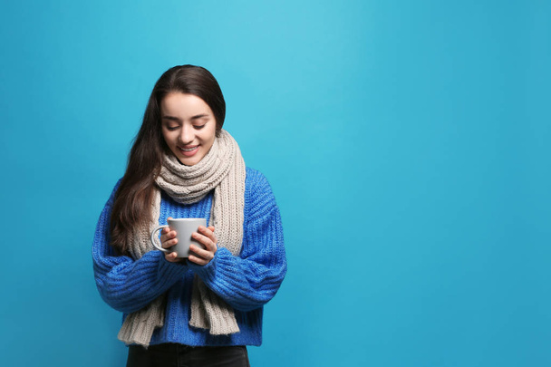 Young woman in sweater with cup of hot coffee on color background, space for text. Winter season - Foto, imagen