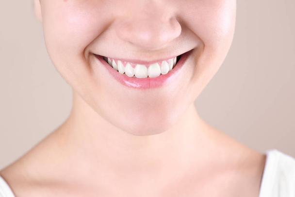 Νεαρή γυναίκα με το όμορφο χαμόγελο στο χρώμα φόντου, κοντινό πλάνο - Φωτογραφία, εικόνα