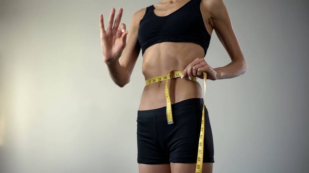 Fille mince mesurant la taille avec ruban adhésif, montrant ok, l'anorexie comme maladie mentale
 - Photo, image