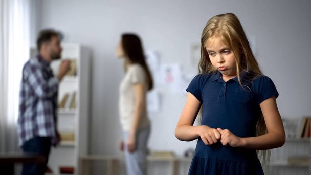 Frightened girl nervously twisting fingers, scared by parents quarrel, violence - Фото, изображение