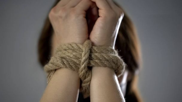 Woman hands tied up with rope, human trafficking, kidnapped woman, hostage - Foto, afbeelding