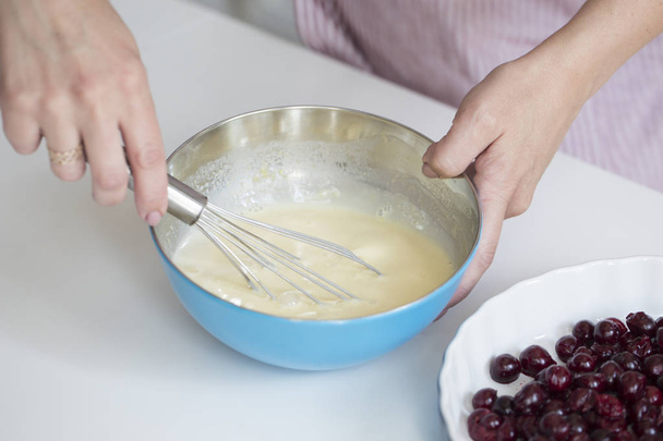 Jovem cozinhando na cozinha.Clafoutis torta de cereja. preparação de bolo francês com cerejas
 - Foto, Imagem