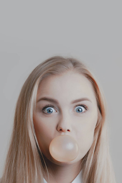 Young playful cute blonde inflates bubble of gum. Emotions and lifestyle - Fotó, kép