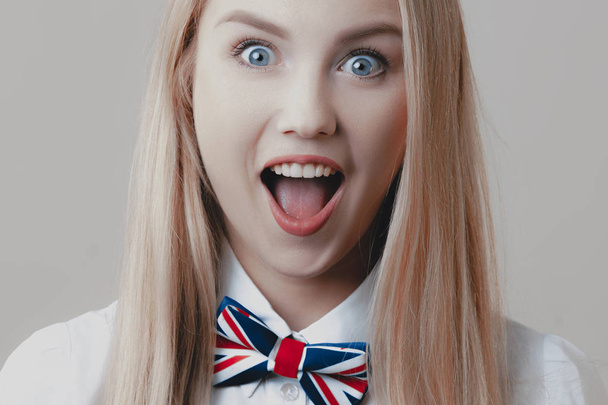 Young playful cute blonde with bow tie opens her mouth in surprise. Emotions and lifestyle - 写真・画像
