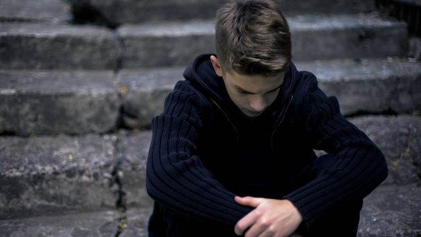 Sad teen sitting on old cracked steps, feeling grief and sorrow, parents loss - Foto, Imagem