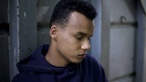 Shy afro-american teenager under influence of bad company, hopelessness in life - 写真・画像