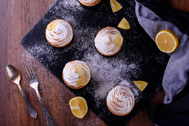 Zitronenmuffins mit Eiweißcreme auf Schiefertafel mit Puderzucker und Honig - Foto, Bild