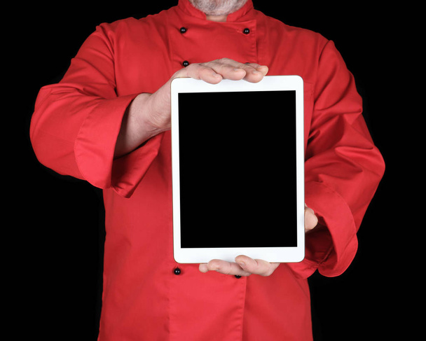 шеф-повар в красной униформе держит белый электронный планшет с черным чистым экраном, копировальное место
  - Фото, изображение