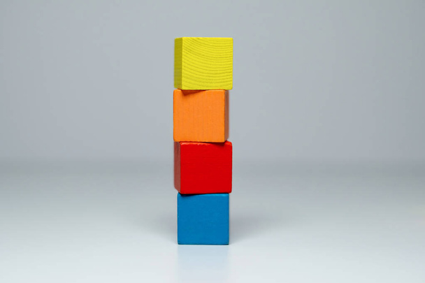 Четыре деревянных детских блока разных цветов, сложенных в высокой башне
 - Фото, изображение