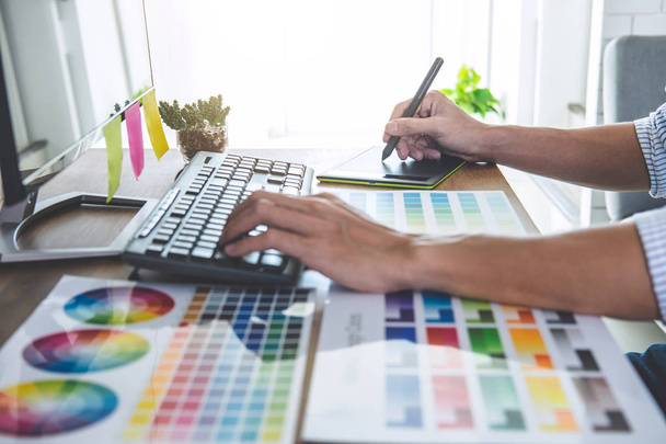 Imagem de designer gráfico criativo masculino trabalhando na seleção de cores e desenho em tablet gráficos no local de trabalho com ferramentas de trabalho e acessórios no espaço de trabalho. - Foto, Imagem