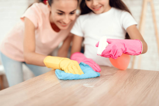 Mamá y su hija están limpiando en casa. Limpie los estantes y la mesa
. - Foto, Imagen