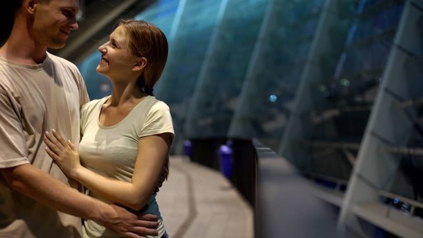 Man hugging woman on romantic evening near city shopping center, dating, closeup - Fotografie, Obrázek