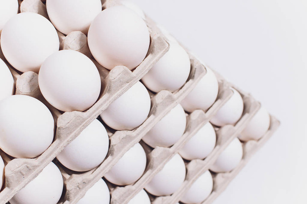 Ovos brancos de uma galinha em embalagem de cartão inofensiva em um contexto branco. 5 embalagens
 - Foto, Imagem