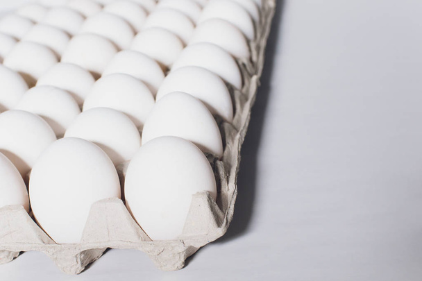 White eggs of a hen in harmless, cardboard packing on a white background. - Foto, Imagen