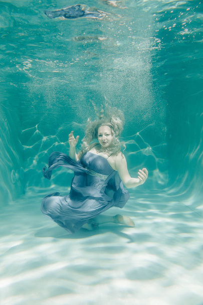 chubby sexy woman in grey evening long dress swimming underwater on her holidays and enjoy with relax - Foto, afbeelding