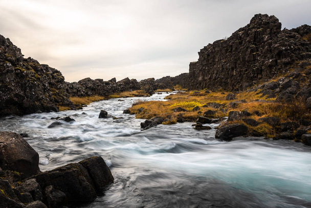 Peřejí potok protékající vulkanity na Islandu na zamračený podzimní den. Rozmazaný pohyb. - Fotografie, Obrázek