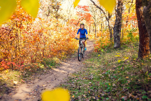 Ciclismo en el bosque. Chica monta en bicicleta en un sendero forestal. Mujer montando su bicicleta en el parque. Recorrido en bicicleta. Viaja a lugares pintorescos. Árboles de otoño
. - Foto, Imagen