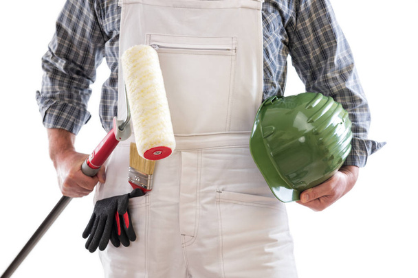 Маляра працівника з білим роботи Спецодяг, тримає в руці роликові для малювання. Оснащений шолом і захисні рукавички. Ізольовані на білому тлі.  - Фото, зображення