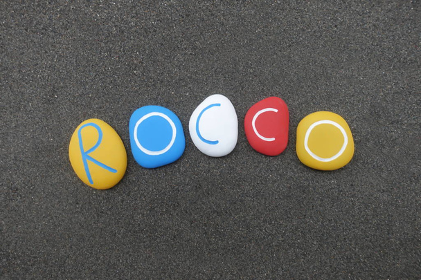 Rocco, męskie imię z kolorowych kamieni nad czarnym wulkanicznym piaskiem - Zdjęcie, obraz