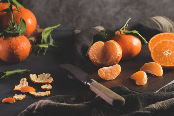 Fresh mandarin oranges or tangerines with leaves on textured dark background - 写真・画像