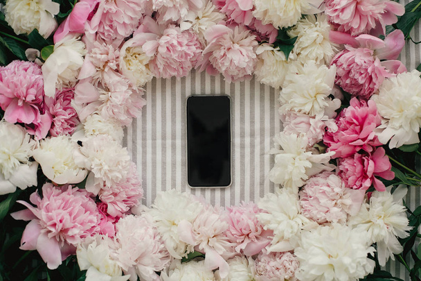Phone with empty screen in peonies frame flat lay on rustic table cloth. Space for text. Greeting card mockup. Happy mothers day. International Womens Day. Valentines day. - Photo, Image