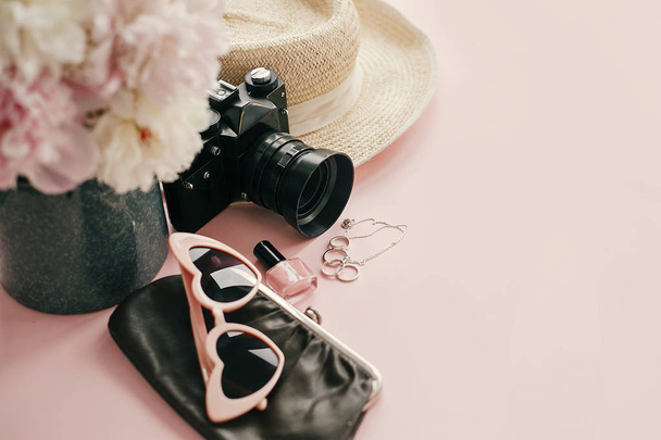 国際女性の日。ピンクの牡丹、写真カメラ、レトロなサングラス、宝飾品、マニキュア、帽子、財布コピー スペースとパステル ピンクの紙にスタイリッシュなヌード イメージ。こんにちは、春のコンセプト. - 写真・画像