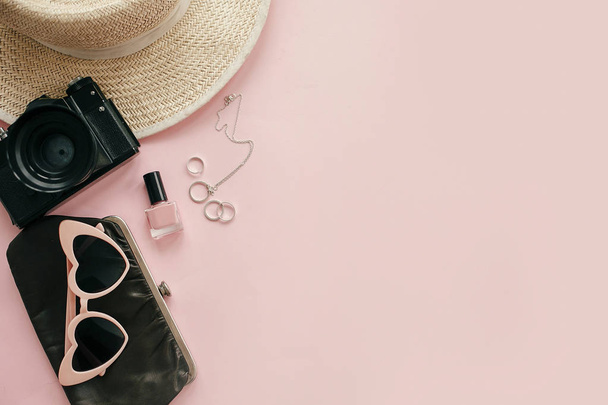 International Women's Day flat lay. Stylish girly image of photo camera, retro sunglasses, jewelry, nail polish, hat, purse on pastel pink paper with copy space.  Hello spring concept. - Photo, image