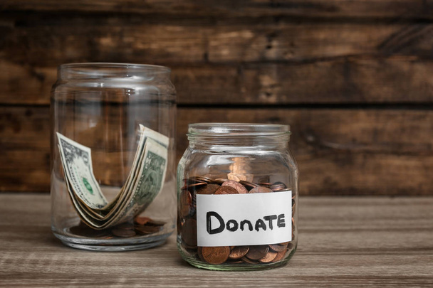 Donation jars with money on wooden table - Foto, imagen