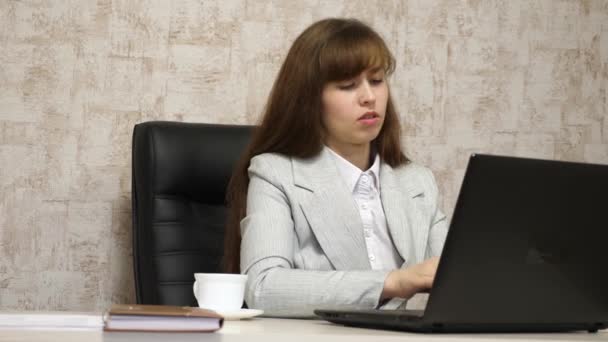 schönes Mädchen sitzt im Bürostuhl und tippt auf dem Laptop. junge Geschäftsfrau, die am Computer arbeitet. Mädchen plaudert auf Laptop - Filmmaterial, Video